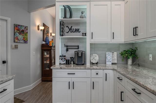 bar with decorative backsplash, baseboards, and wood finished floors