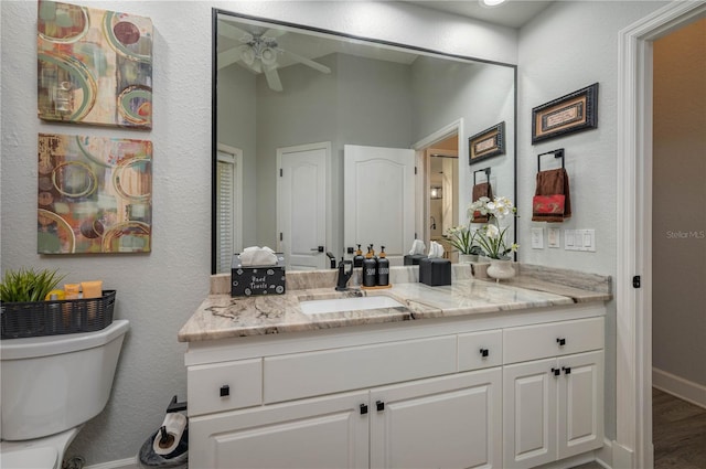 bathroom featuring vanity, wood finished floors, baseboards, ceiling fan, and toilet