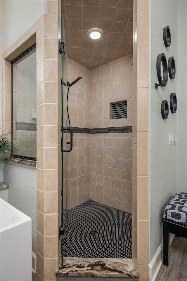 bathroom featuring baseboards, wood finished floors, and a shower stall