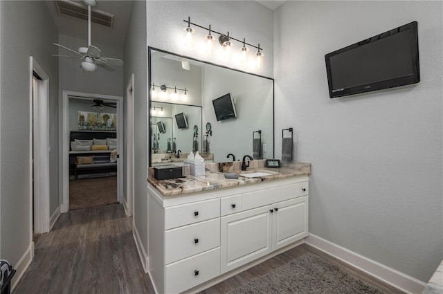 bathroom with visible vents, vanity, baseboards, and wood finished floors