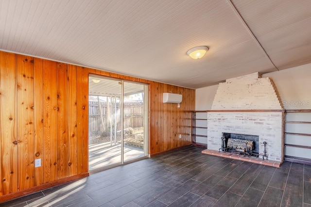 unfurnished living room with a wall unit AC, wood walls, a fireplace, wood finished floors, and baseboards