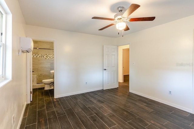 unfurnished bedroom with a wall unit AC, baseboards, and dark wood-style flooring