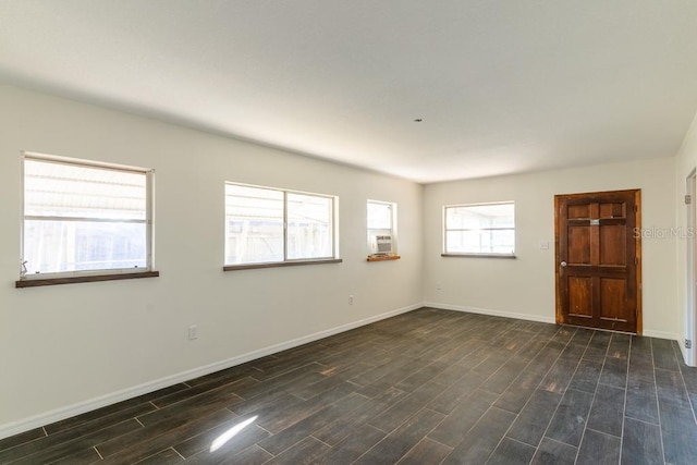 unfurnished room featuring baseboards and dark wood-style flooring