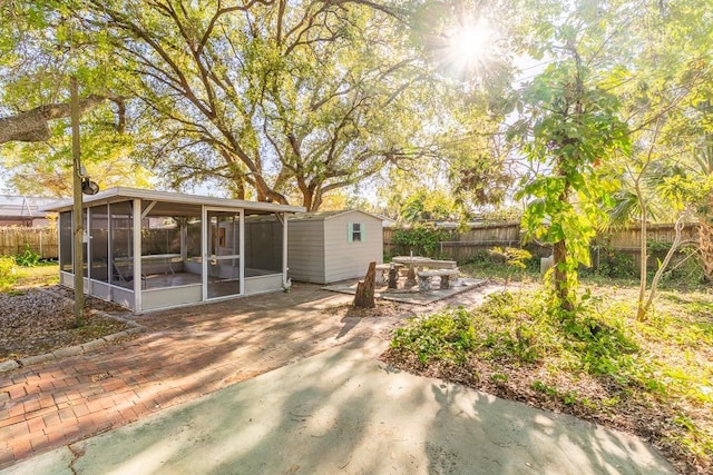 view of yard with an outbuilding, a sunroom, a fenced backyard, and a patio