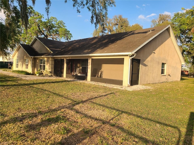 exterior space featuring stucco siding, a lawn, and a sunroom