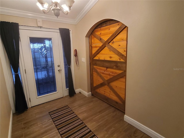 entrance foyer with baseboards, an inviting chandelier, wood finished floors, and crown molding