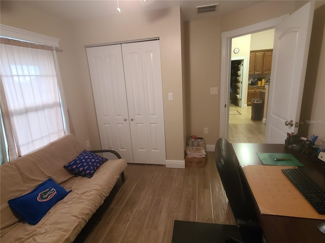 bedroom with light wood-style floors, visible vents, a closet, and baseboards