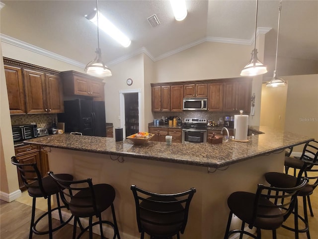 kitchen with visible vents, a breakfast bar, tasteful backsplash, stainless steel appliances, and vaulted ceiling