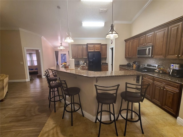 kitchen featuring a kitchen bar, appliances with stainless steel finishes, tasteful backsplash, and crown molding