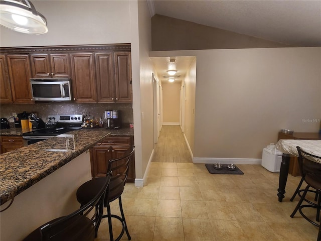 kitchen with vaulted ceiling, backsplash, baseboards, and appliances with stainless steel finishes