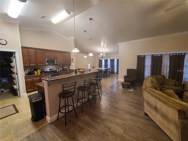 kitchen with visible vents, stainless steel appliances, a kitchen breakfast bar, open floor plan, and backsplash