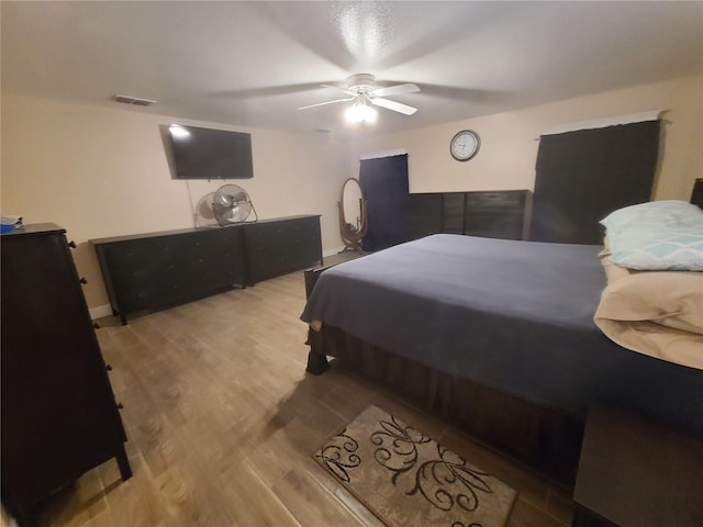 bedroom with ceiling fan, visible vents, and wood finished floors