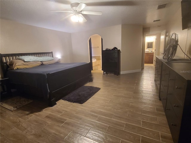 bedroom featuring visible vents, ensuite bath, arched walkways, baseboards, and wood tiled floor