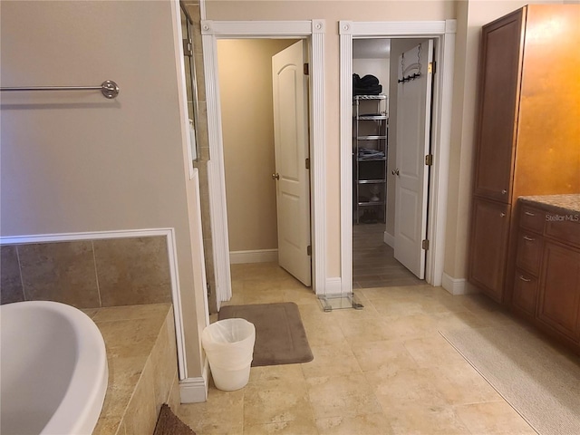 bathroom with a sink, baseboards, a bathtub, and a spacious closet