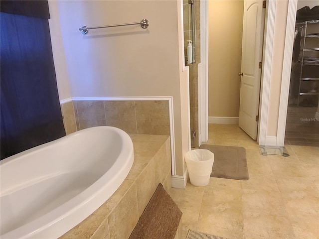 full bathroom featuring tile patterned flooring, baseboards, and a relaxing tiled tub