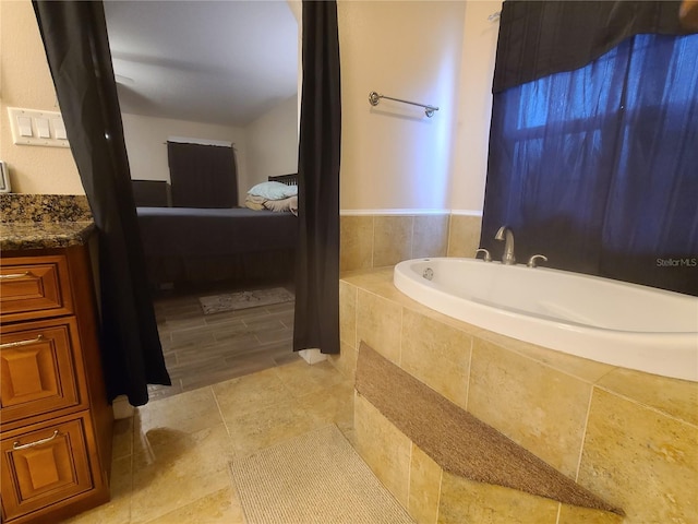 ensuite bathroom featuring connected bathroom, a bath, and vanity