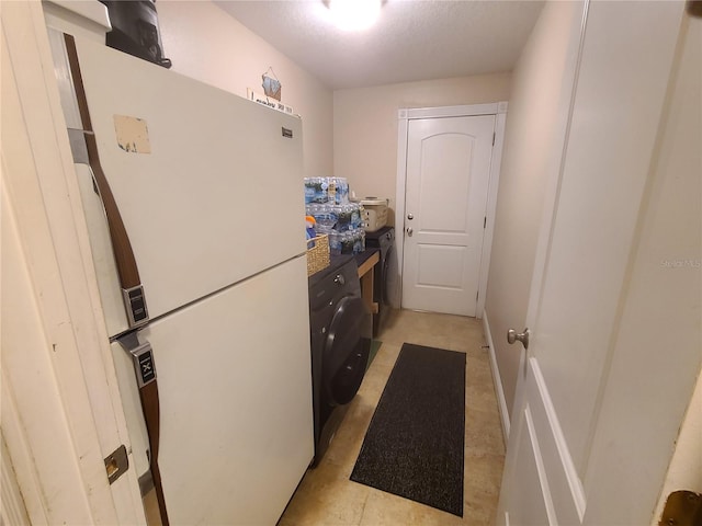 kitchen featuring dark countertops, washer / dryer, and freestanding refrigerator