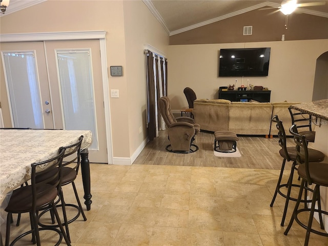 interior space with baseboards, visible vents, ceiling fan, vaulted ceiling, and crown molding