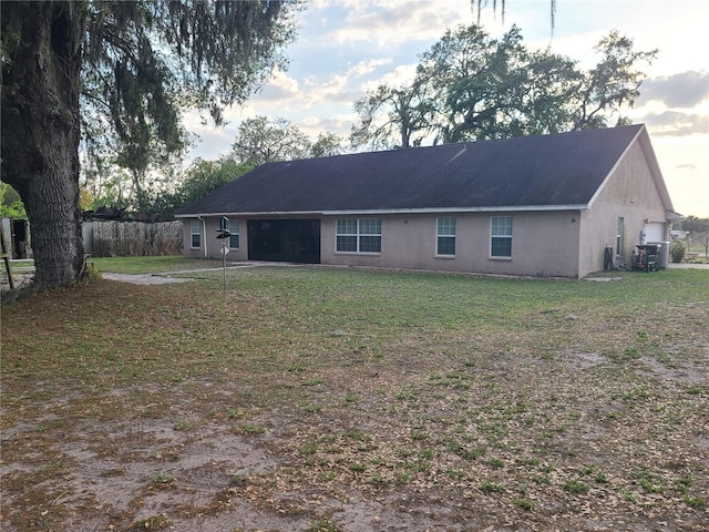 rear view of house featuring a lawn and stucco siding