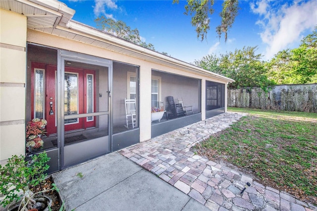 property entrance with stucco siding, fence, and a yard
