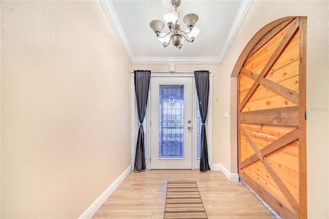 doorway featuring baseboards, ornamental molding, an inviting chandelier, and light wood finished floors