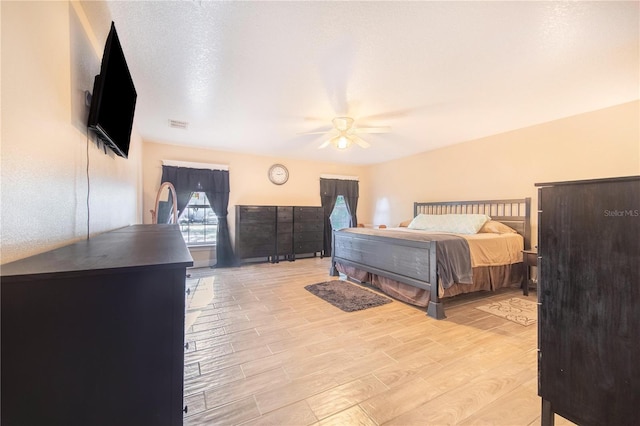 bedroom featuring a textured ceiling, ceiling fan, and light wood-type flooring