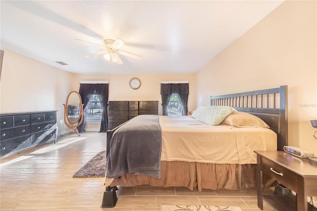 bedroom with ceiling fan, visible vents, and wood finish floors