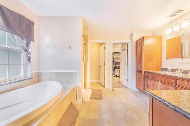 bathroom with vanity, a walk in closet, a shower stall, visible vents, and a bath