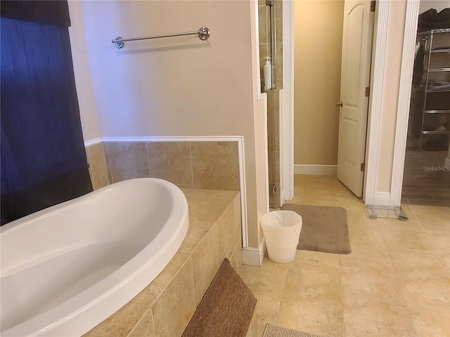 full bathroom with a relaxing tiled tub, tile patterned floors, and baseboards