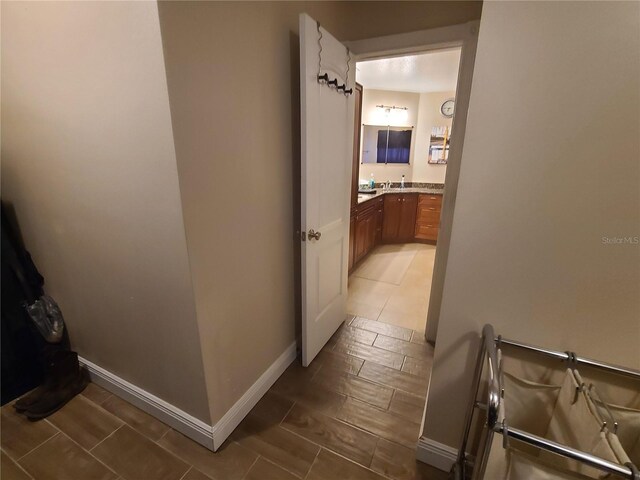 corridor with baseboards, wood tiled floor, and a sink