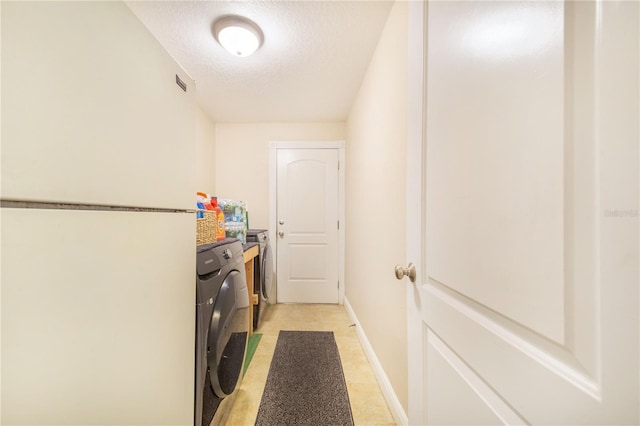 laundry area featuring baseboards, separate washer and dryer, a textured ceiling, visible vents, and laundry area