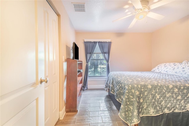 bedroom featuring wood tiled floor, baseboards, visible vents, and a ceiling fan