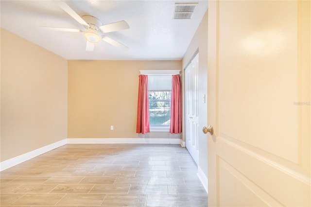 spare room featuring baseboards, visible vents, light wood-type flooring, and a ceiling fan