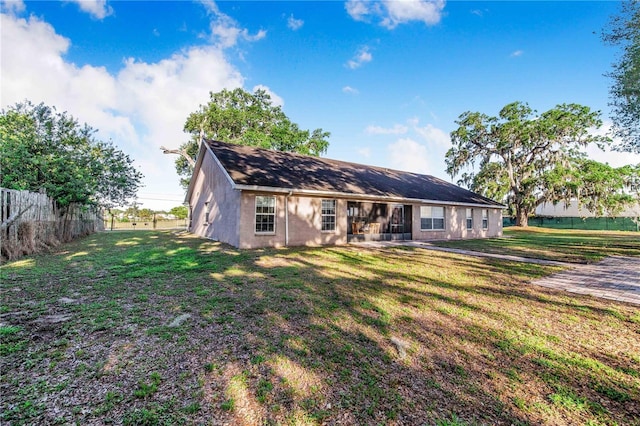 back of property with a yard, stucco siding, and fence