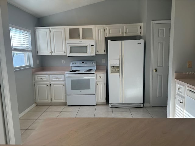 kitchen with light tile patterned floors, white appliances, white cabinets, vaulted ceiling, and light countertops