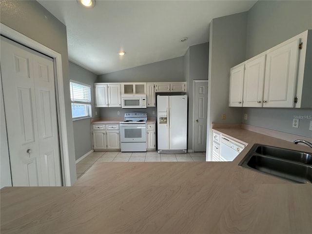 kitchen featuring white appliances, white cabinets, a sink, and light tile patterned floors