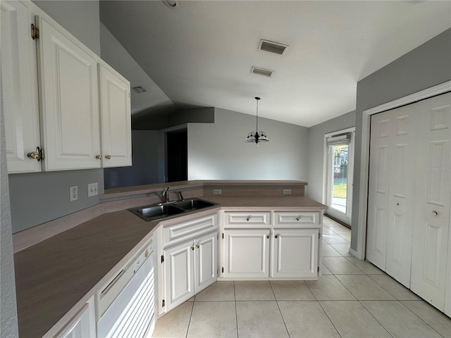 kitchen with light tile patterned floors, dishwasher, a peninsula, white cabinetry, and a sink