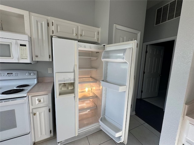 kitchen featuring white appliances, light tile patterned flooring, visible vents, and white cabinetry