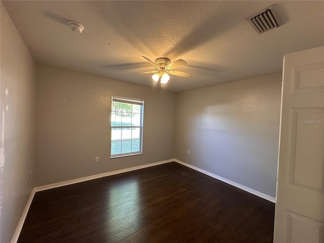 empty room featuring dark wood-style floors, visible vents, a ceiling fan, a textured ceiling, and baseboards