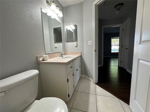 bathroom featuring toilet, tile patterned flooring, baseboards, and a textured wall