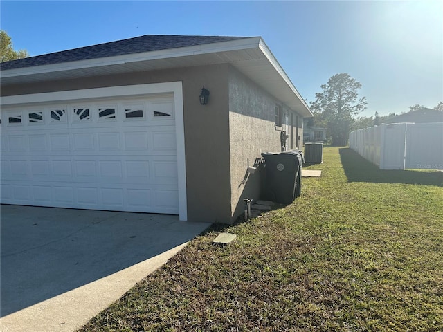 view of home's exterior featuring stucco siding, a lawn, central AC, fence, and driveway