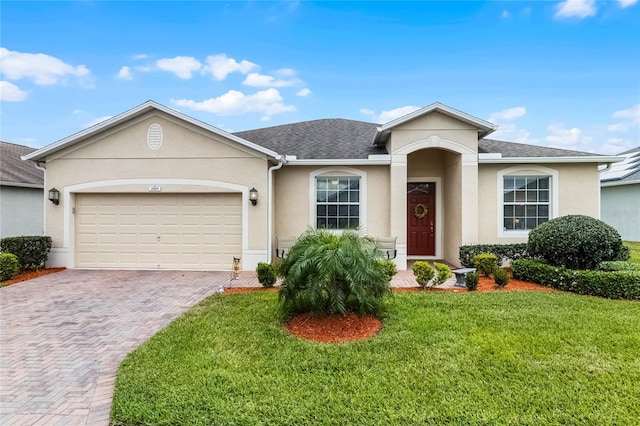 ranch-style home featuring stucco siding, decorative driveway, a front lawn, and an attached garage