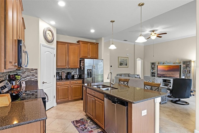 kitchen featuring brown cabinetry, arched walkways, a sink, appliances with stainless steel finishes, and open floor plan