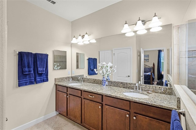 bathroom featuring a sink, baseboards, double vanity, and tile patterned floors