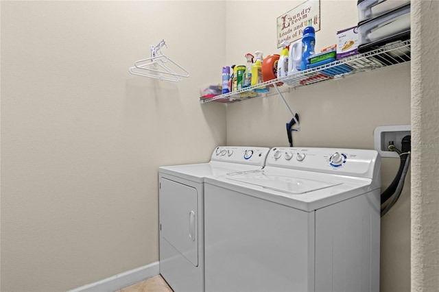 clothes washing area with baseboards, washing machine and dryer, and laundry area