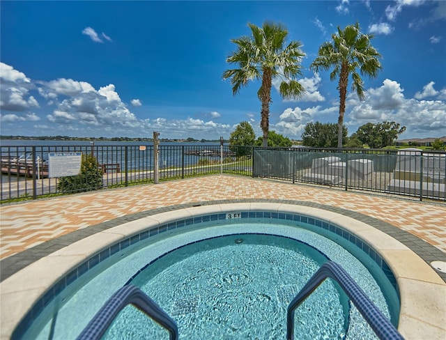 view of swimming pool with a hot tub and fence