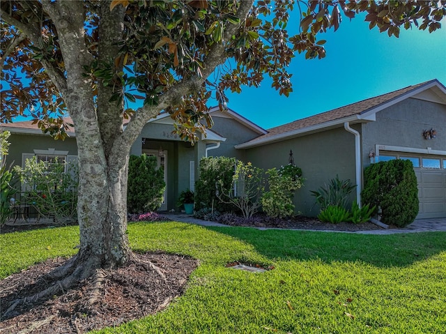 view of front of property with stucco siding, an attached garage, and a front yard