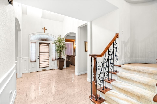 entryway featuring arched walkways, stairway, and a decorative wall