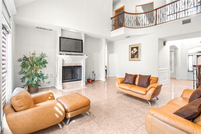 living room featuring visible vents, a high ceiling, arched walkways, and a high end fireplace