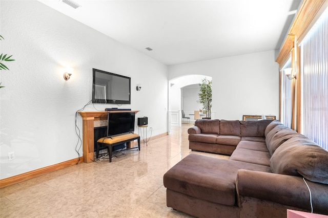 living room featuring baseboards, visible vents, and arched walkways
